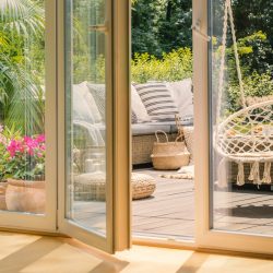 Real photo of a hanging armchair and a rattan sofa with cushions on a wooden patio behind the door